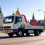 A modest, affordable tow truck with a simple, clean design parked on a Moscow street, with recognizable Moscow architecture such as the Kremlin dome silhouettes in the background, under a clear sky. The scene conveys reliability and cost-effectiveness without any text, logos, or signage.
